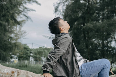 Side view of young man sitting in forest