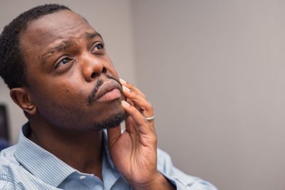 Close-up of young man looking away against wall