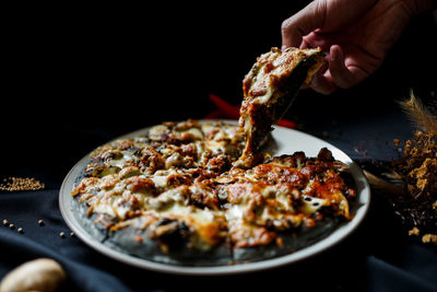 Close-up of hand holding pizza in plate