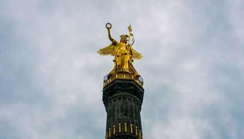 Low angle view of angel statue against cloudy sky