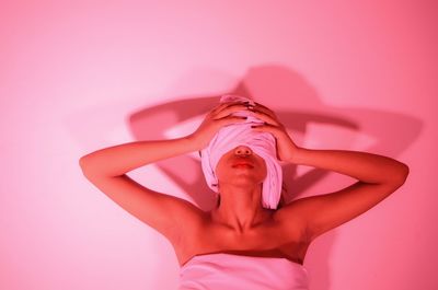 Woman wrapped in towels against white wall