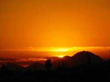 Scenic view of silhouette mountains against orange sky