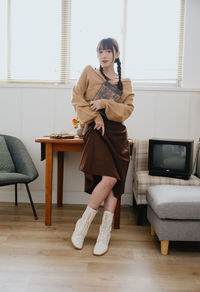 Young woman using phone while sitting on sofa at home