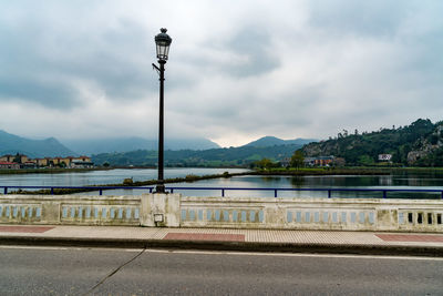 Street lights by river against sky
