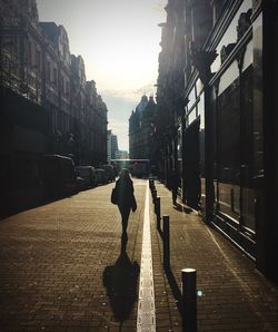 Rear view of silhouette woman walking on street in city
