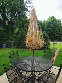 Empty chairs and table in park against sky