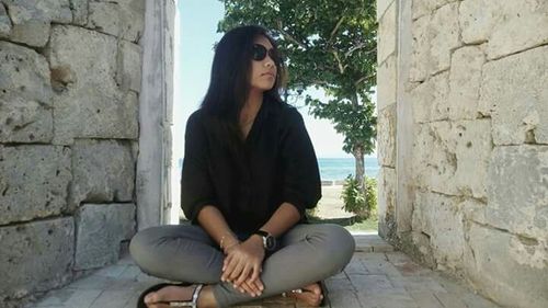 Young woman leaning on wall