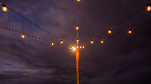 Low angle view of illuminated street pole lights against sky
