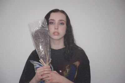 Portrait of woman holding drink against white background