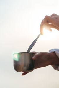 Close-up of hand holding wineglass against white background