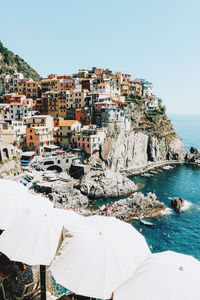 Buildings by sea against clear sky