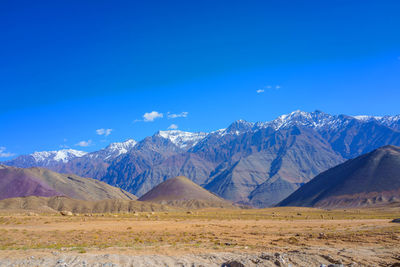 Scenic view of snowcapped mountains against blue sky