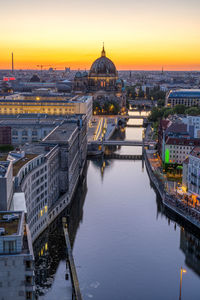 Bridge over river in city during sunset