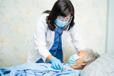 Doctor wearing mask examining patient in hospital