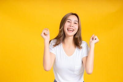 Portrait of a smiling young woman against yellow background