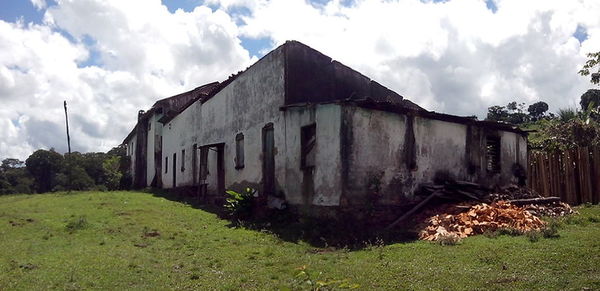 Abandoned building on field against cloudy sky