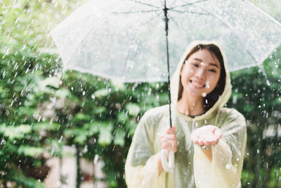 Portrait of woman with umbrella standing in rain