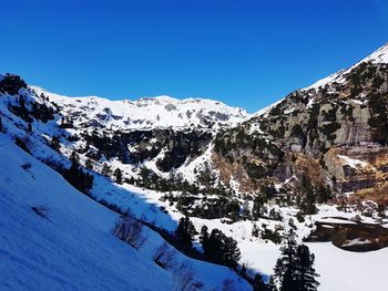 Scenic view of snowcapped mountains against clear blue sky