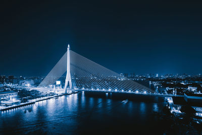 Illuminated bridge over river at night