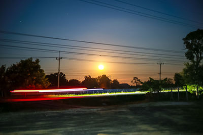 Light trails on road against sky during sunset