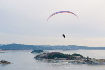 People paragliding over sea against sky