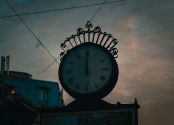 Low angle view of clock against sky at sunset