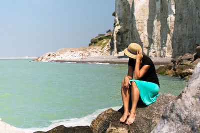 Woman sitting on rock on beach