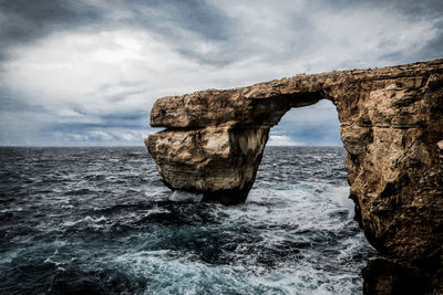 Rock formation in sea against sky