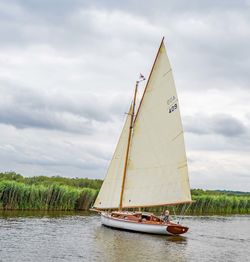 Sailboat sailing in river against sky