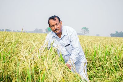 Portrait of man standing on field against sky