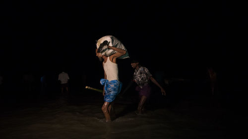 Young woman standing on sand at beach during night