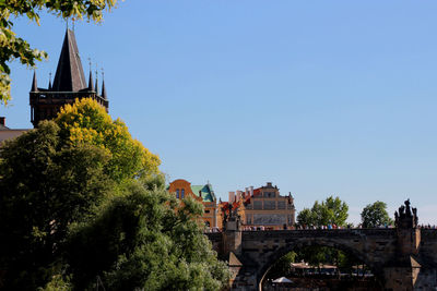 Arch bridge amidst trees and buildings against sky