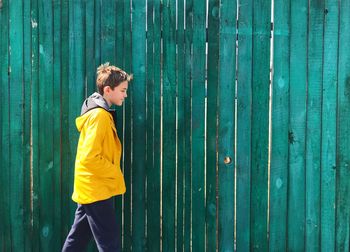 Side view of boy looking away against blue wall