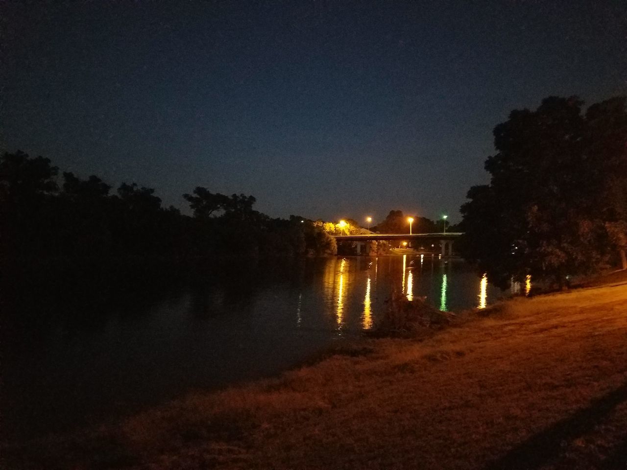 night, illuminated, water, reflection, tree, sky, city, tranquility, outdoors, nature, dark, tranquil scene, scenics, no people, beauty in nature, standing water, growth