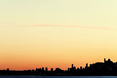 Silhouette buildings against clear sky during sunset