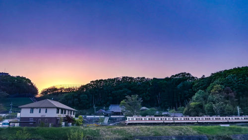 Houses and trees against sky during sunset