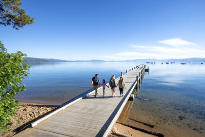 A family walks on a pier on a beautiful day in south lake tahoe, ca