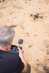 Back view of senior man with telecontrol and drone