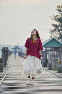 Full length of woman walking on footbridge against sky