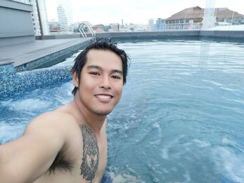 Portrait of smiling shirtless man swimming in pool