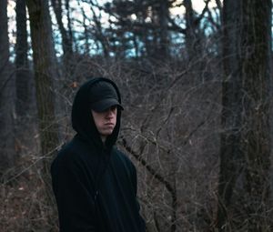 Portrait of man standing against bare trees in forest