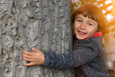 Portrait of smiling boy against tree trunk