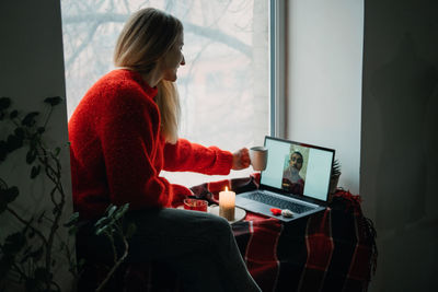 Woman using phone while sitting on table