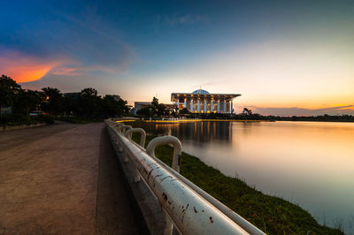 Road by lake leading towards mosque at sunset