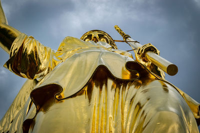 Low angle view of cross sculpture against sky