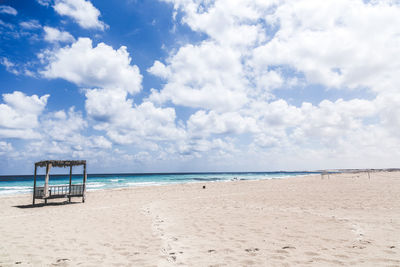 Distant view of bed on beach against cloudy sky