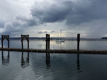 Pier in sea against cloudy sky