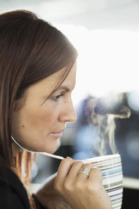 Businesswoman talking on headphones while having coffee in office