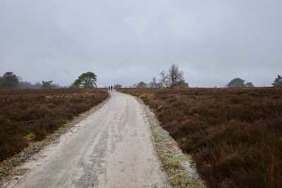 Road amidst field against sky