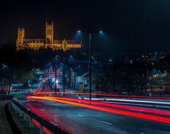 Light trails on city street by buildings at night